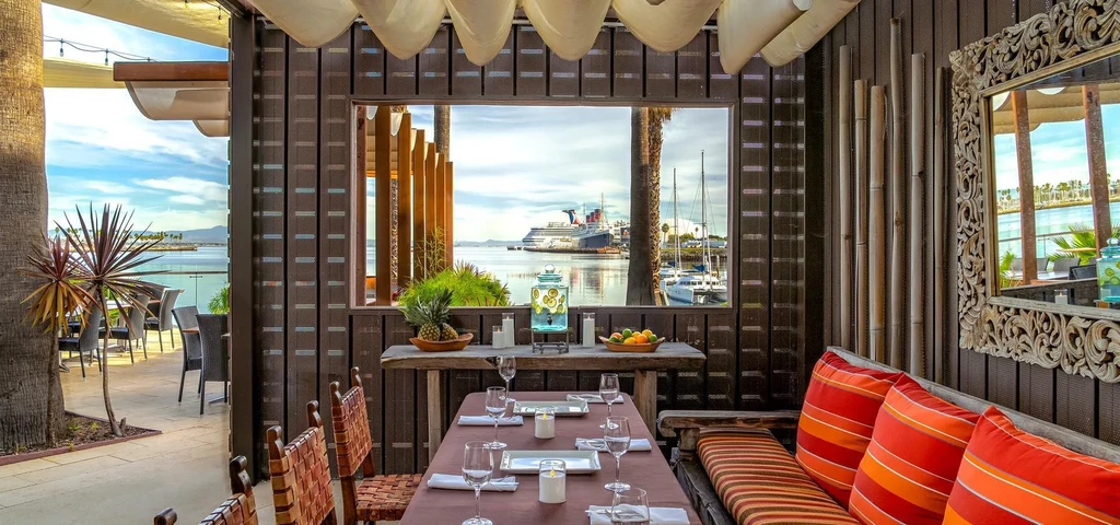 Tropical restaurant interior with communal table and harbor view.
