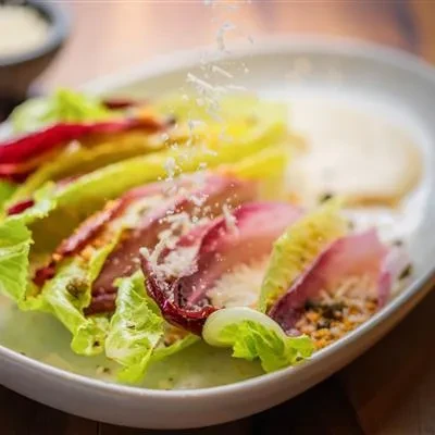 Vibrant radicchio salad with falling parmesan on a white dish.