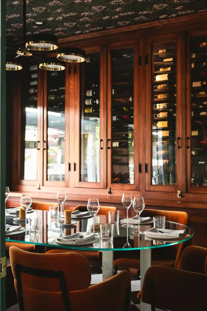 Empty restaurant dining area with set table and extensive wine wall.