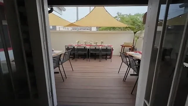 Empty outdoor dining patio with set tables and yellow shade sails.