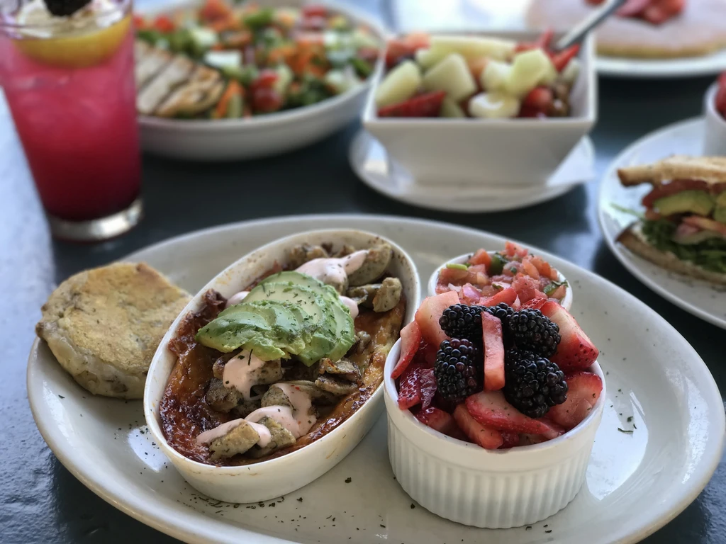 Breakfast spread with egg casserole, avocado, fresh berries, and pink beverage.