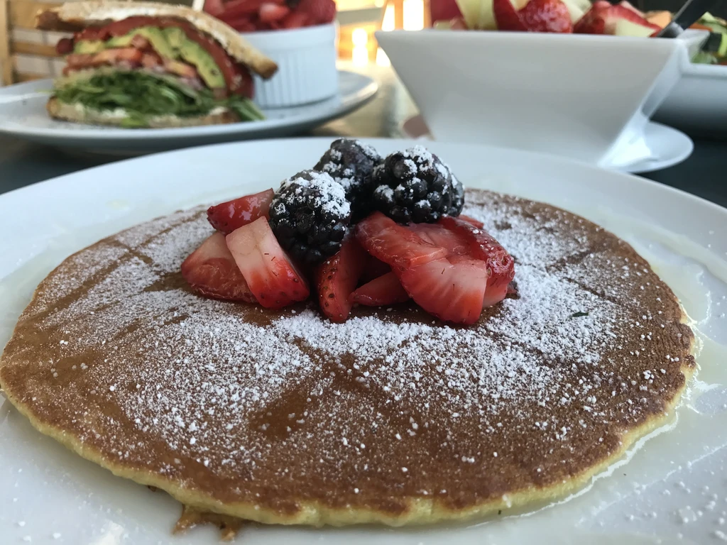 Golden-brown pancake topped with powdered sugar, strawberries, and blackberries.