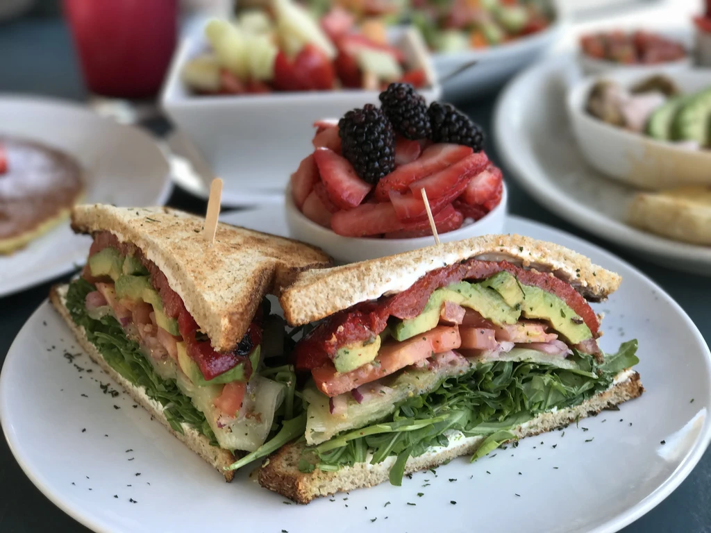 Toasted sandwich filled with vegetables and berries on a white plate.