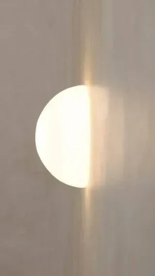 Modern disc wall light emitting warm light on a wall.