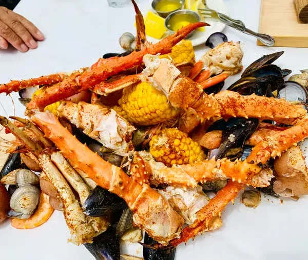 Large seasoned pile of crab legs, corn, mussels, shrimp, and clams.