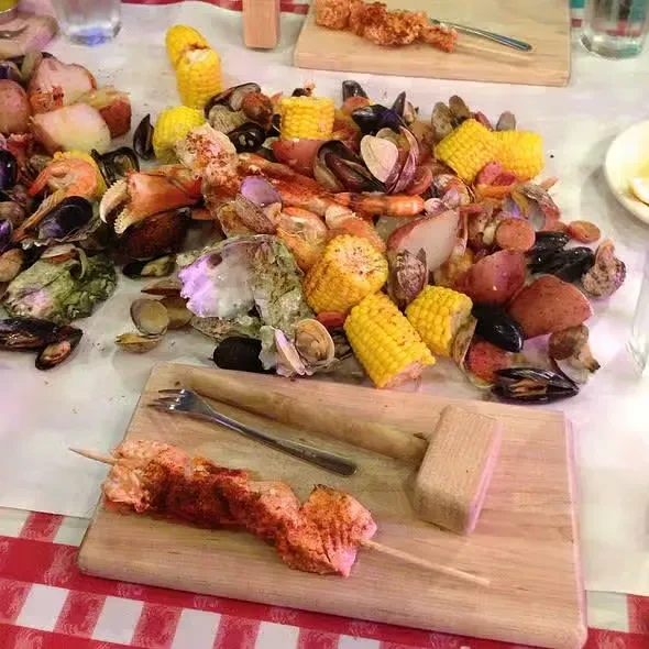 Abundant seafood boil feast with crab, shrimp, corn, and mallet.
