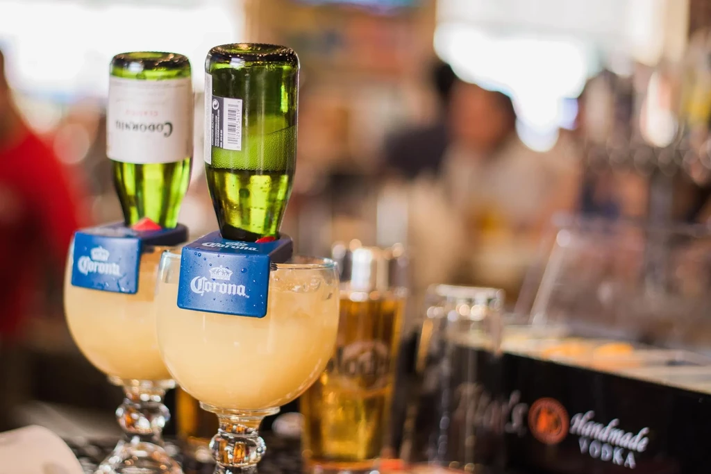 Two Coronarita-style cocktails with inverted green bottles in a bar setting.