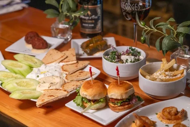 Vibrant spread of small plates, appetizers, and wine on a wooden table.