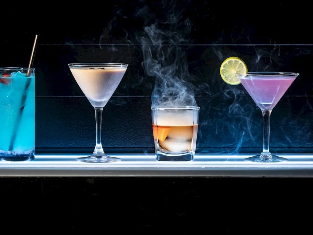 Four distinct cocktails on a glowing surface, one smoking dramatically.