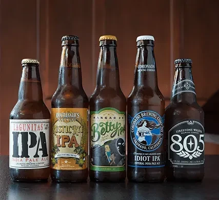 Five distinct bottled IPAs arranged on a dark surface.