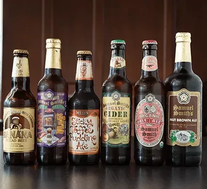 Six diverse craft beer and cider bottles on a dark surface.
