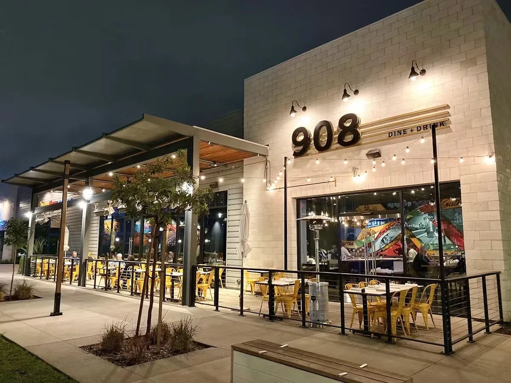 Night exterior of '908 DINE + DRINK' restaurant with string-lit patio.
