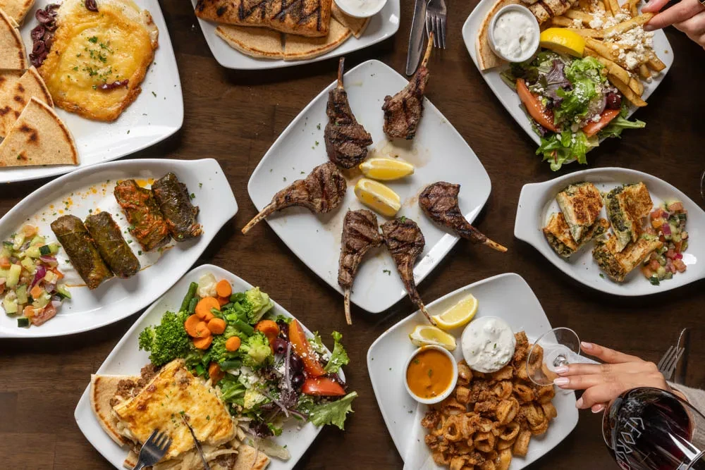 Overhead view of a table laden with Mediterranean dishes and hands.