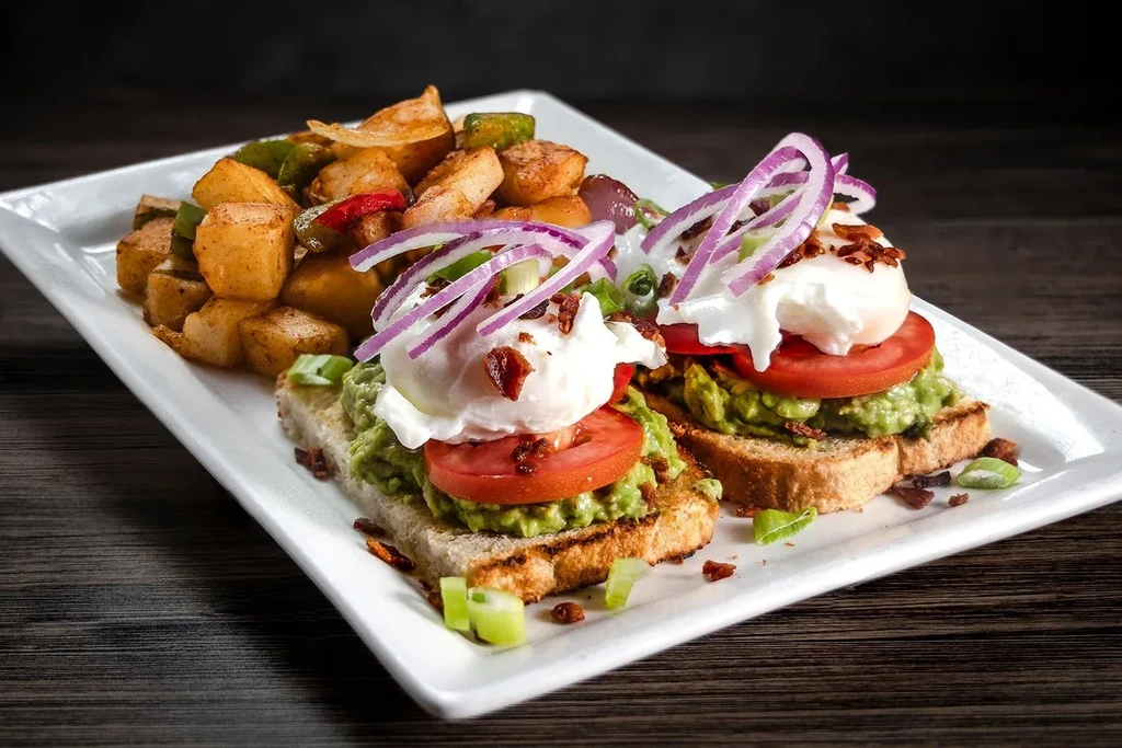 Avocado toast with poached egg, bacon, and seasoned potatoes.