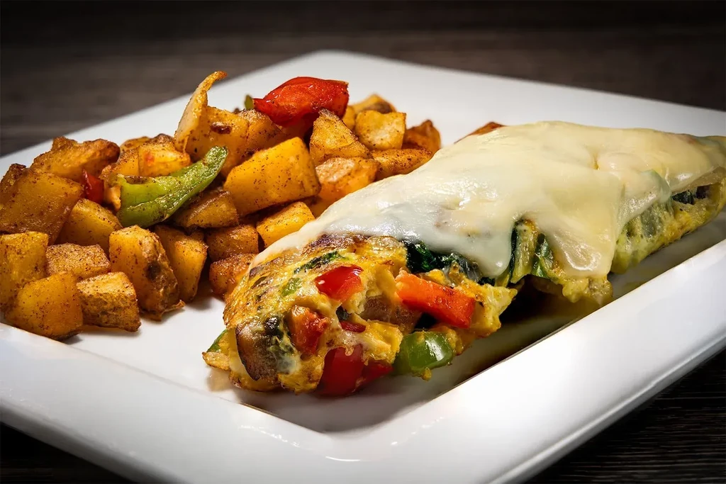 Melted cheese omelet with peppers and a side of roasted diced potatoes.