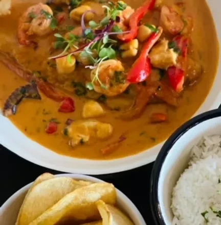 Seafood stew with shrimp, scallops, rice, and potato wedges.