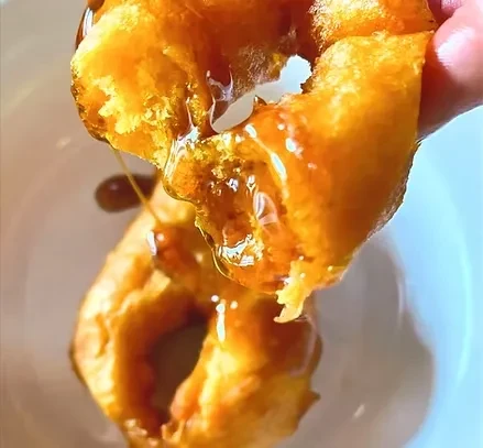 Golden-brown fried dough pulled apart, thick amber glaze dripping from edges.