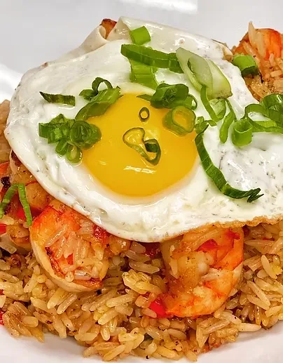 Fried rice topped with shrimp, a sunny-side-up egg, and green onions.