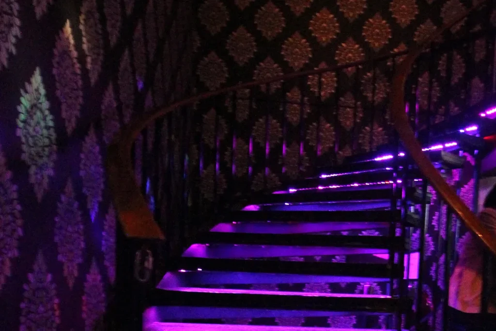 Purple LED-lit winding staircase with ornate gold patterned walls.