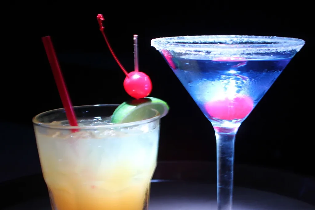 Two vibrant cocktails: yellow-orange with lime, and blue with frosted rim.