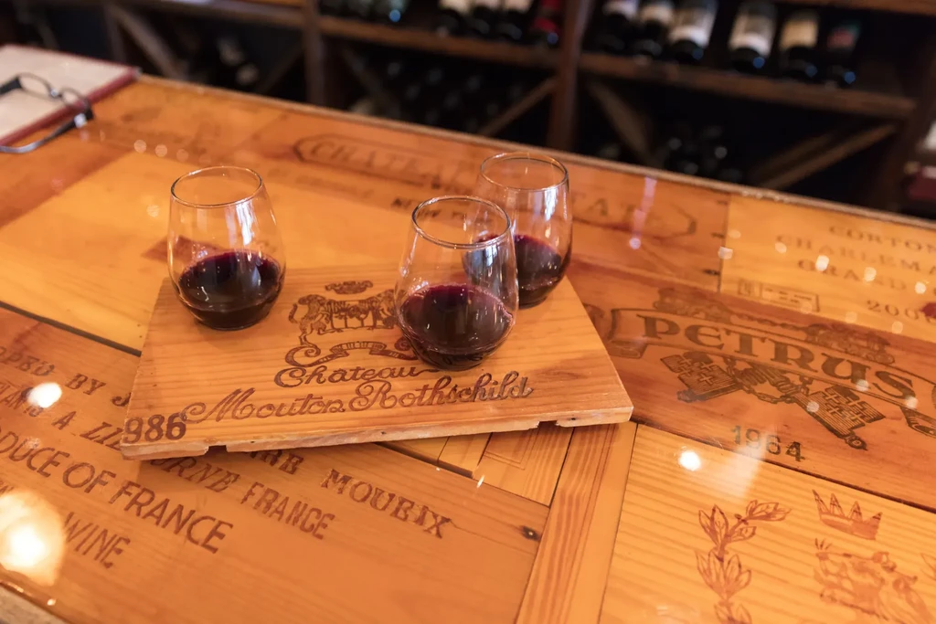 Three stemless red wine glasses on a tray atop wine crate table.