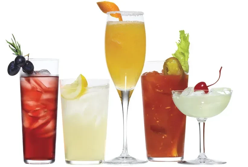 Studio shot of five colorful beverages in different glasses on white.