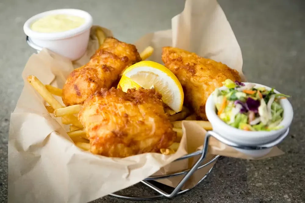 Golden fried fish and chips with lemon, tartar sauce, and coleslaw.