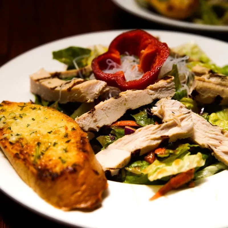 Grilled chicken salad, heart-shaped bell pepper, and garlic bread.