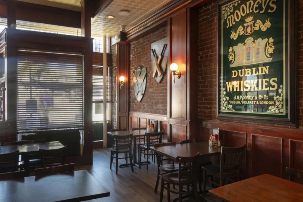 Empty traditional pub interior with brick walls and Mooney's whiskey sign.