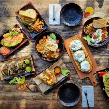 Diverse breakfast and brunch spread with avocado toast, tacos, and eggs.