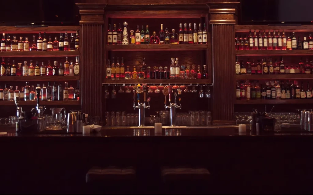 A well-appointed bar with liquor bottles, beer taps, and clean glassware.
