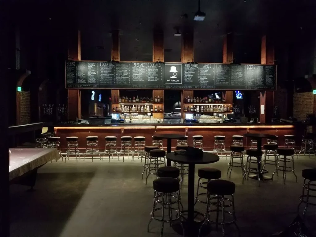 Interior of Mr Furley's bar with a long counter and chalkboard menus.