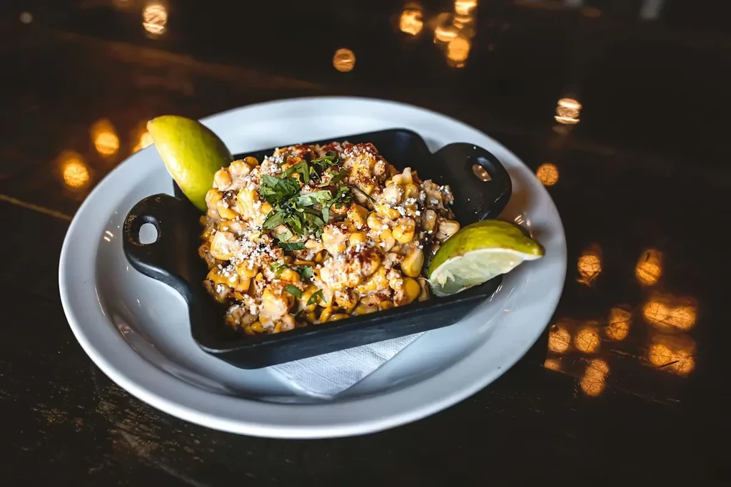 Elote/esquites corn with cheese, chili, cilantro, served in a black skillet.