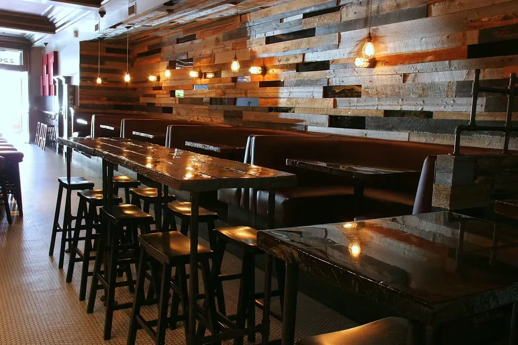 Rustic restaurant with communal tables, booths, and Edison bulb lighting.