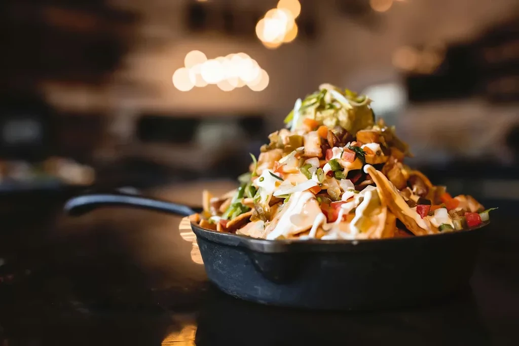Nachos with guacamole, pico de gallo, and creamy sauce in a skillet.