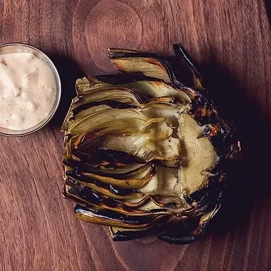 Charred grilled artichoke heart, fanned, with a creamy dipping sauce.