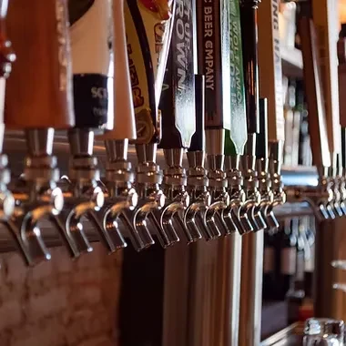 Close-up of ten shiny, branded beer taps in a bar.