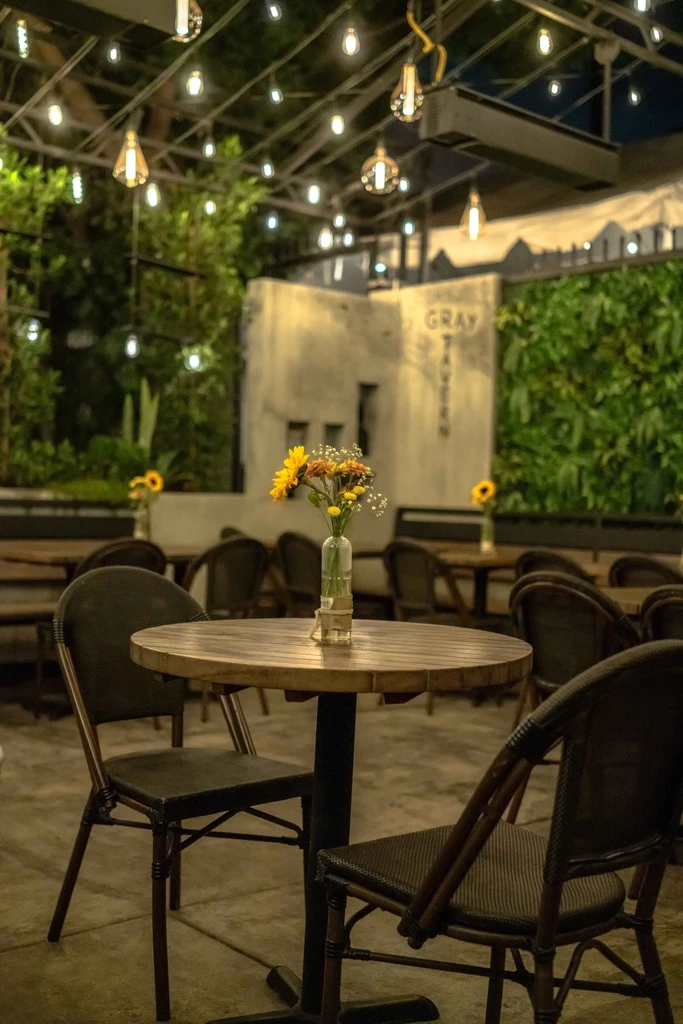 Gray Tavern outdoor dining at night with sunflowers and string lights.
