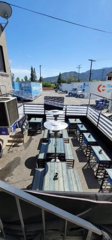 Empty outdoor restaurant patio with distressed tables and heaters.