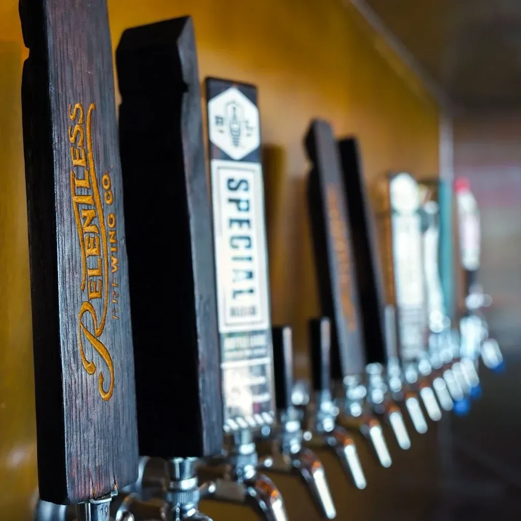 Two beer tap handles are in focus, 'Relentless Brewing Co.' and 'SPECIAL'.