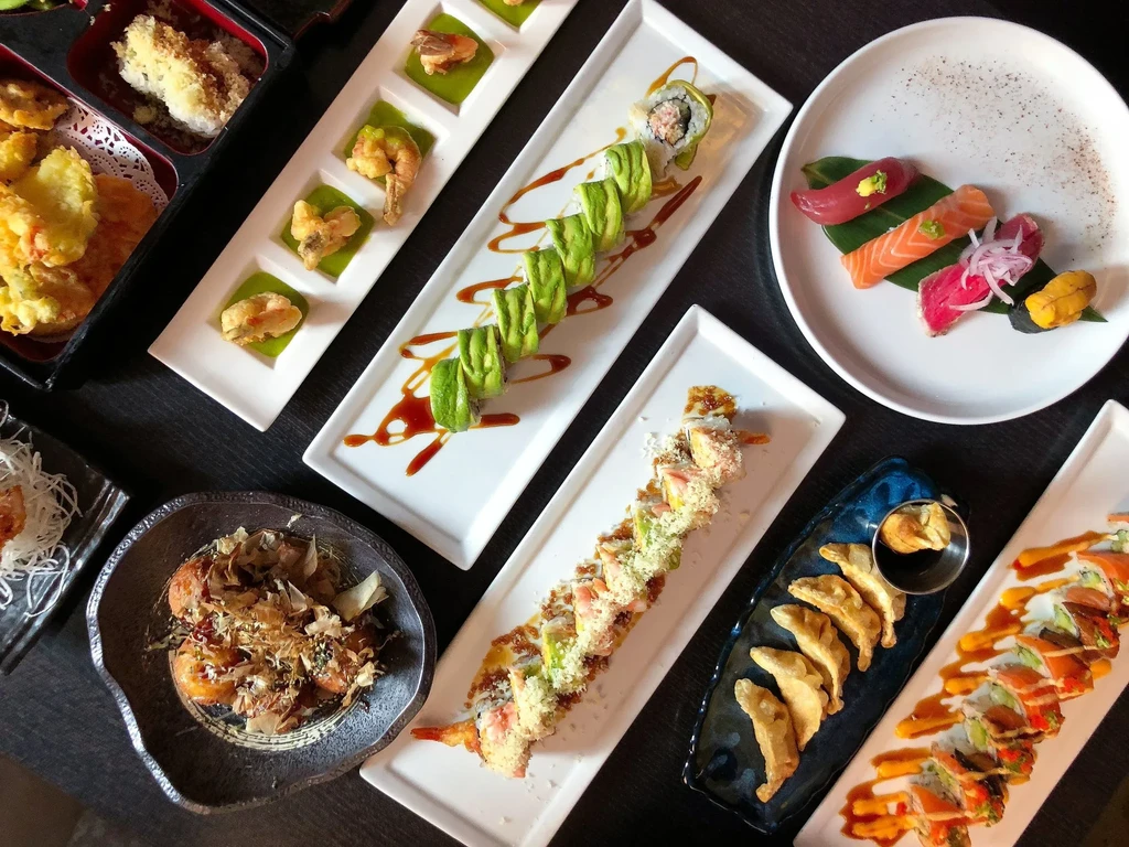 Overhead shot of various Japanese dishes: sushi, sashimi, tempura, takoyaki, gyoza.