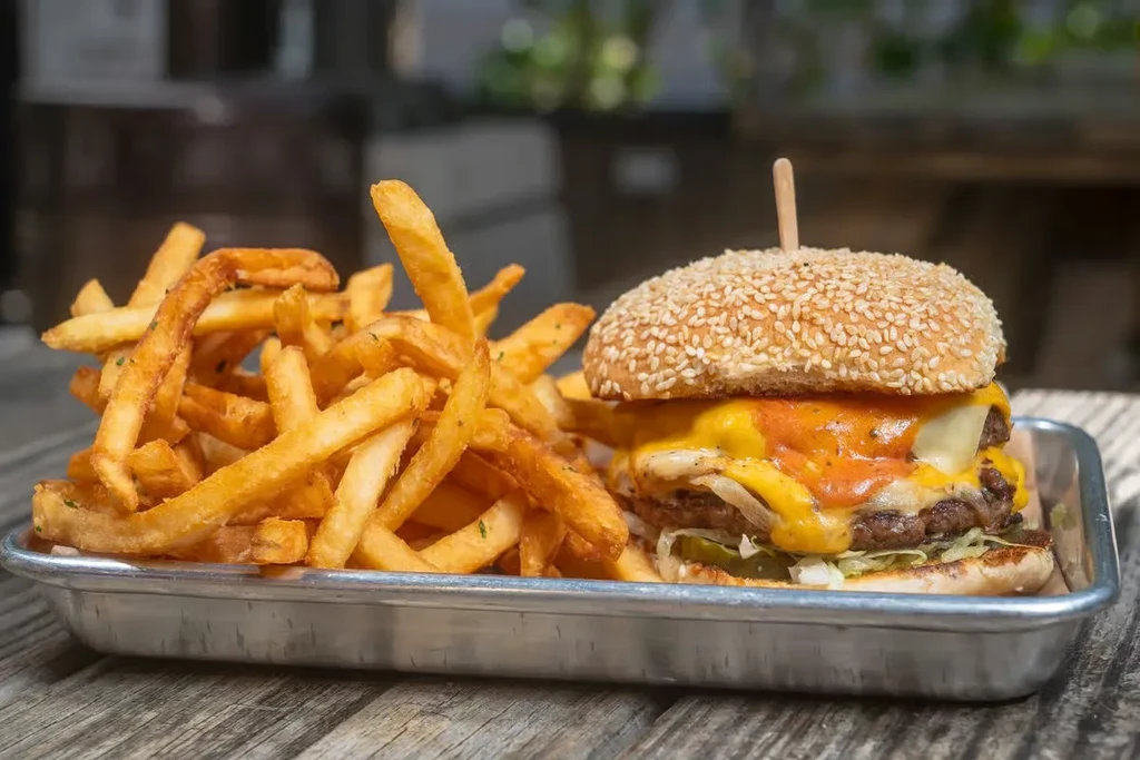 Close-up of a double cheeseburger and fries on a metal tray.