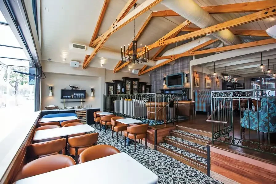 Modern rustic multi-level restaurant interior with dining, bar, and architectural details.