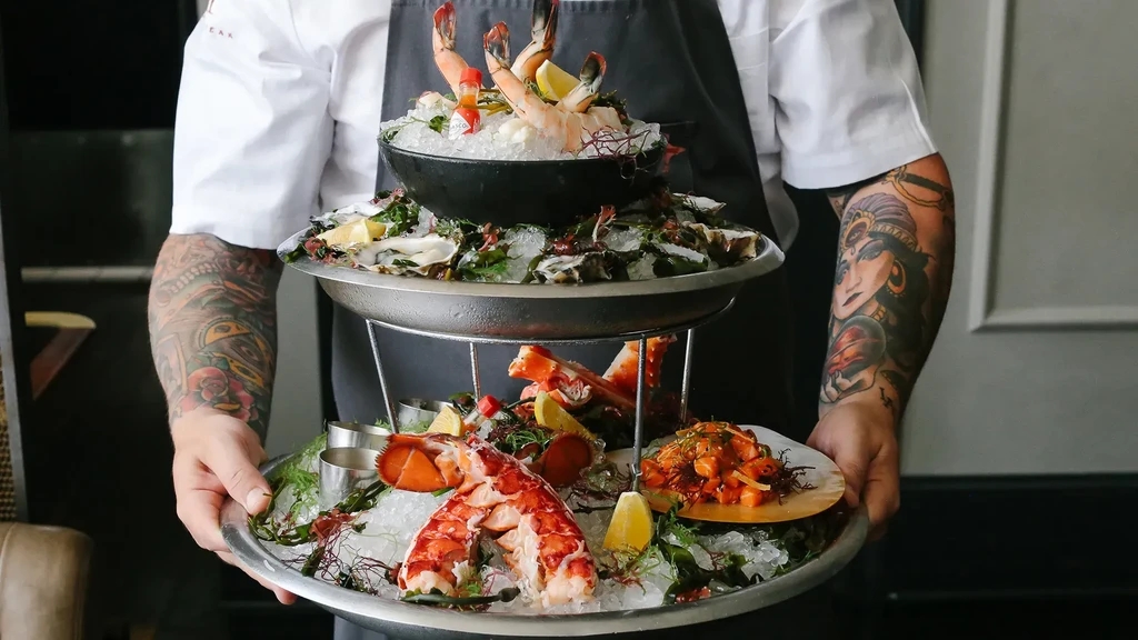 Professional chef holds an elaborate multi-tiered fresh seafood tower.
