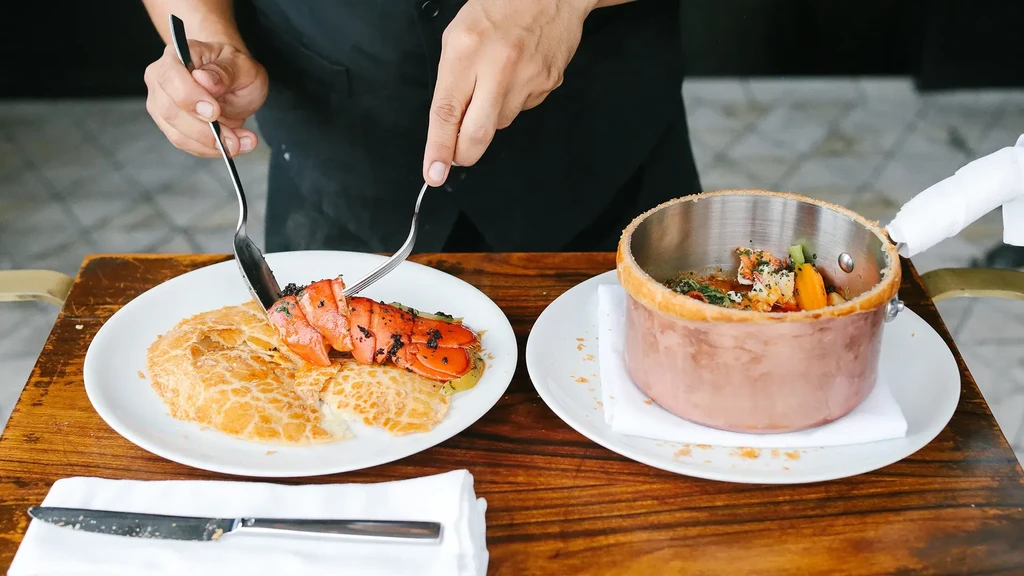 Hands serving a lobster dish and a vegetable pot pie.