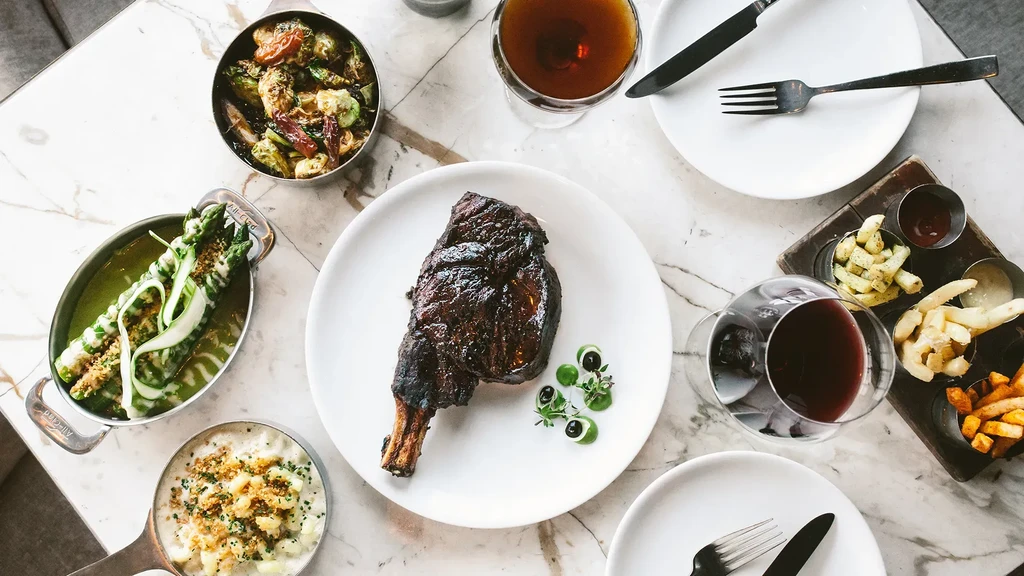 Top-down: Upscale dining table with steak, gourmet sides, and drinks.