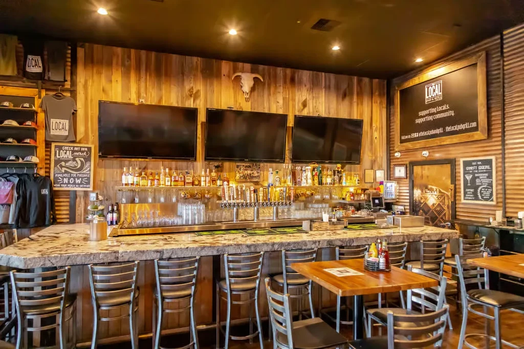 Rustic-modern pub interior with an L-shaped bar and "LOCAL" branding.