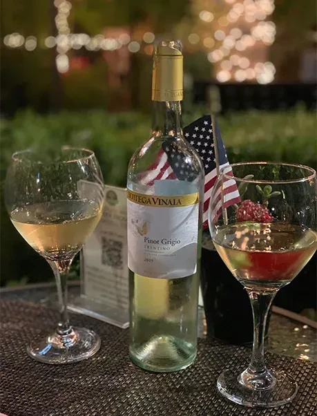 Table setting with white wine, two glasses, and American flag.