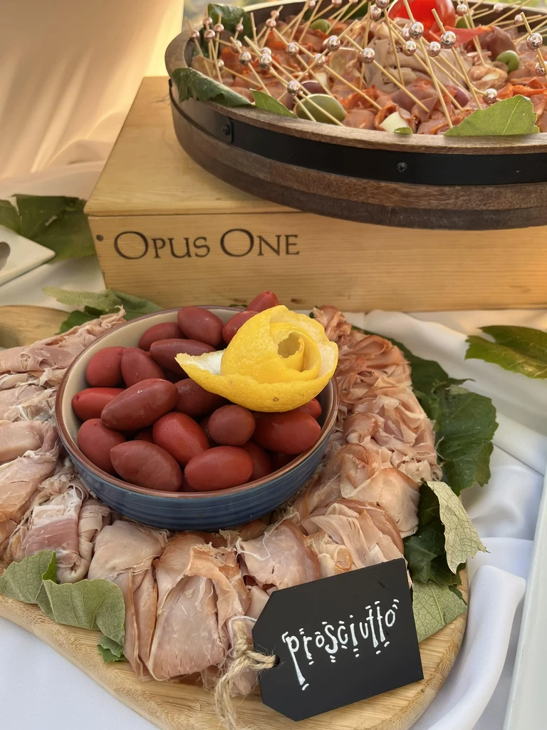Prosciutto, olives, and appetizers on elegant wooden serving boards.