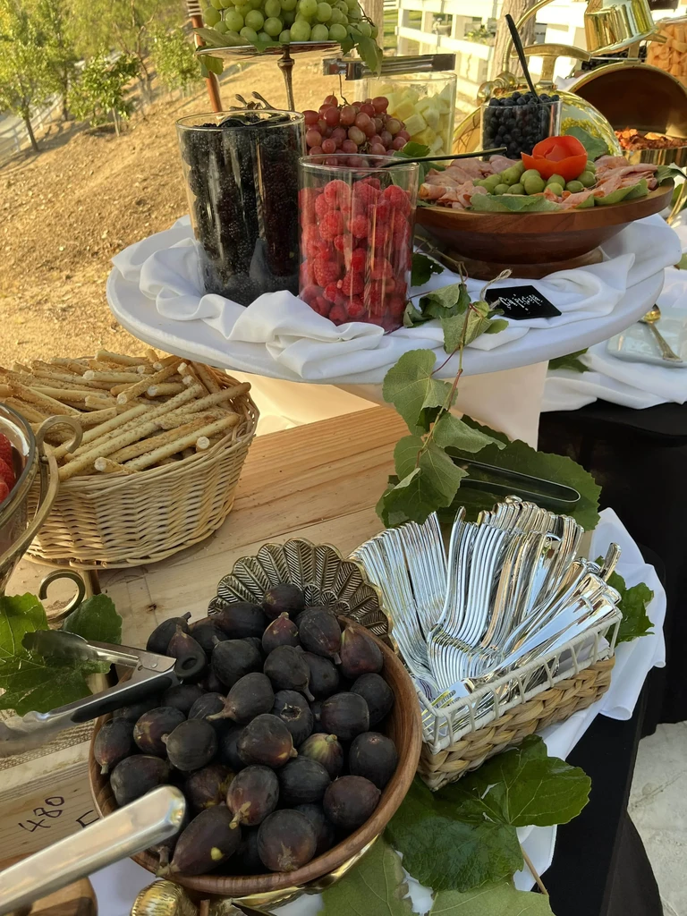 Lavish outdoor buffet spread of fruits, meats, and baked goods.